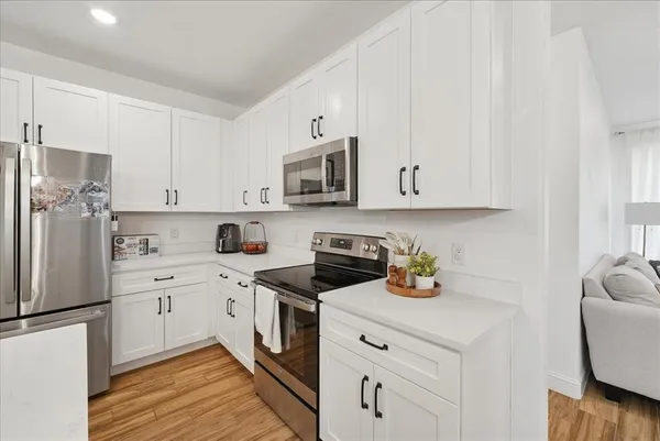 a kitchen with cabinets stainless steel appliances a sink and wooden floor