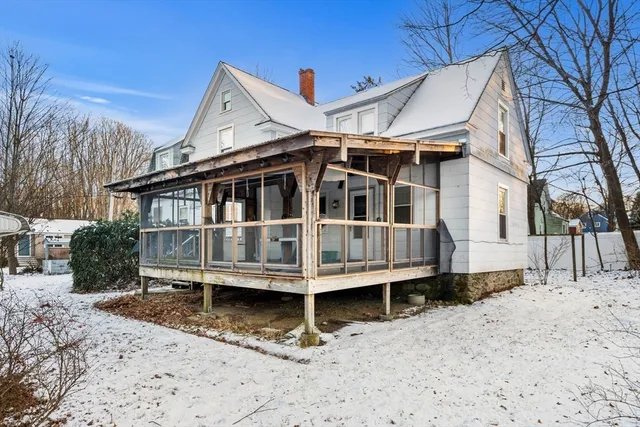 a view of a white house with a yard covered with snow in the background