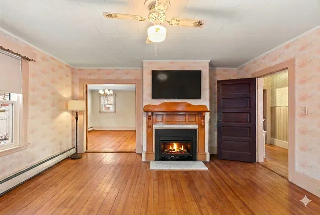 a view of an empty room with wooden floor fireplace and a window
