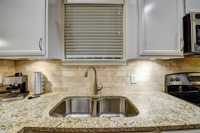 a kitchen with granite countertop a sink and a stove top oven