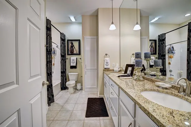 a bathroom with a granite countertop sink mirror vanity and toilet