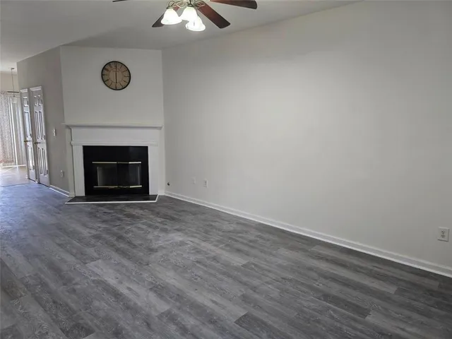 an empty room with wooden floor a fireplace and window
