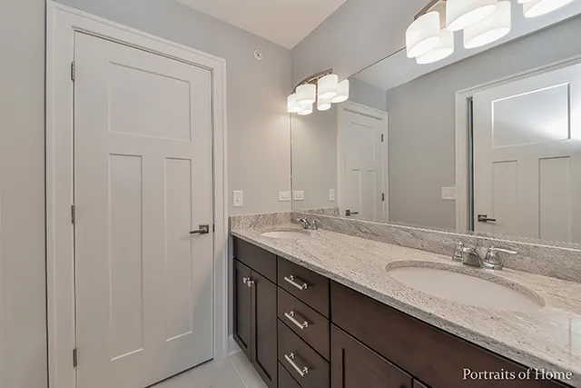 a bathroom with a granite countertop double vanity sink and a mirror