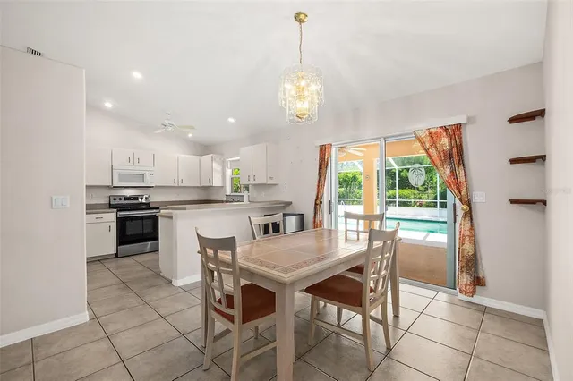 a kitchen with stainless steel appliances granite countertop a stove a refrigerator a sink dishwasher and a dining table with wooden floor