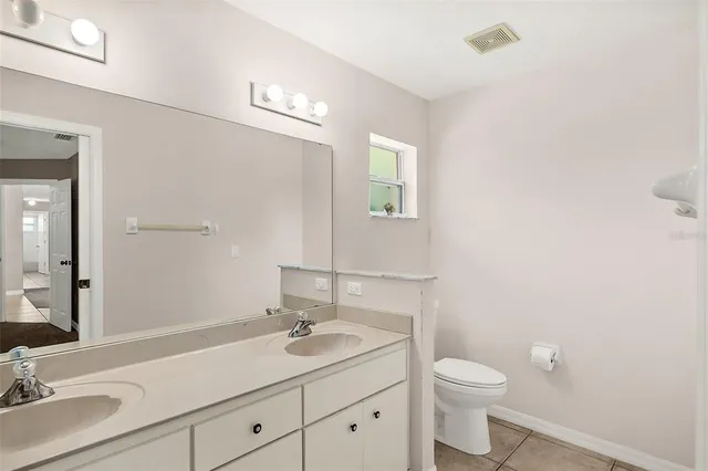 a bathroom with a toilet a sink a mirror and vanity