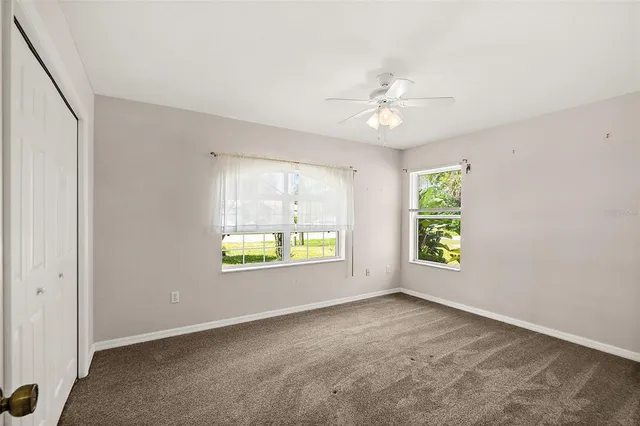 an empty room with a window and a ceiling fan