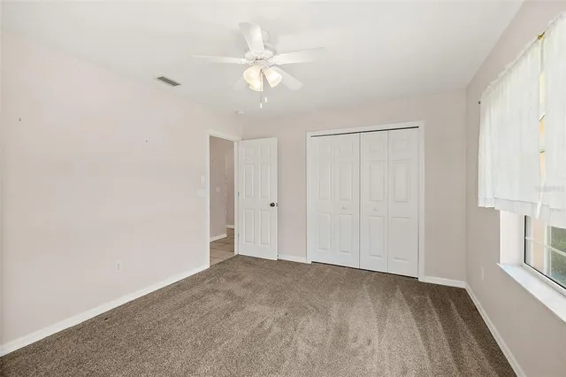 an empty room with windows and fan