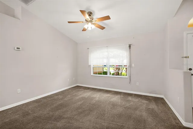 an empty room with windows and ceiling fan