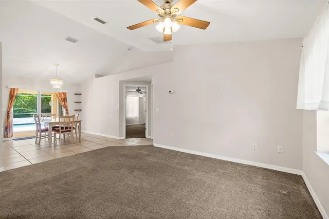 an empty room with chandelier fan and windows