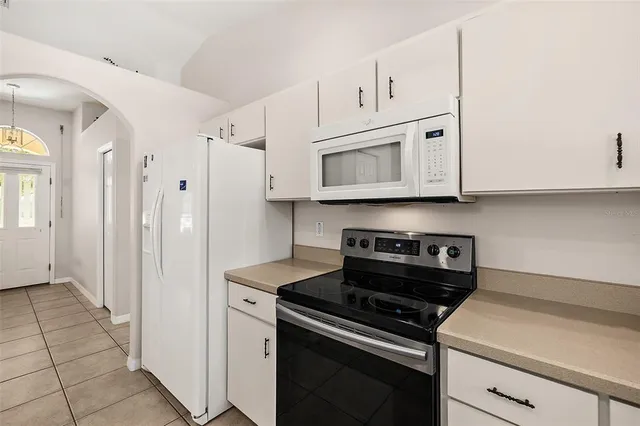 a kitchen with stainless steel appliances granite countertop white cabinets and a stove a refrigerator with white cabinets