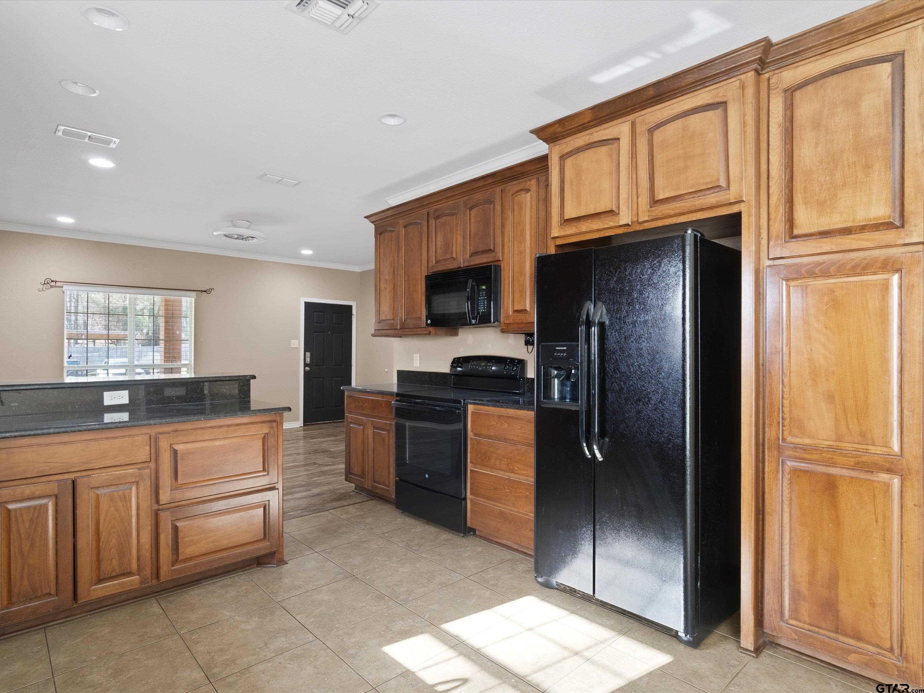 1703 Azalea Street Gilmer, TX 75644 - Photo 24 of 34 a kitchen with granite countertop a refrigerator and a sink