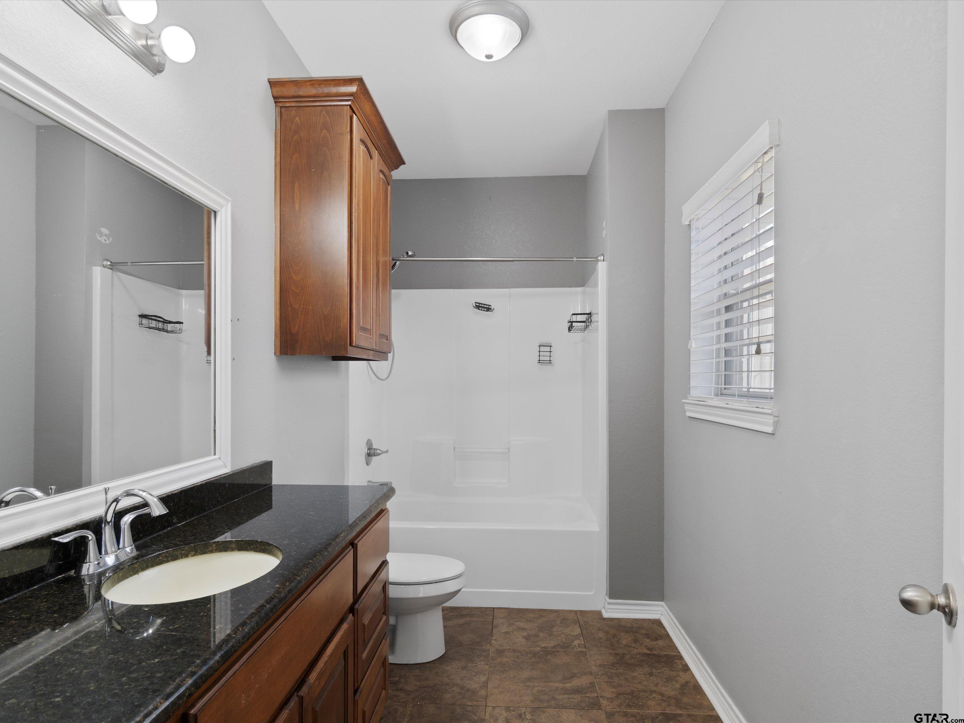 1703 Azalea Street Gilmer, TX 75644 - Photo 30 of 34 a bathroom with a granite countertop sink toilet and shower