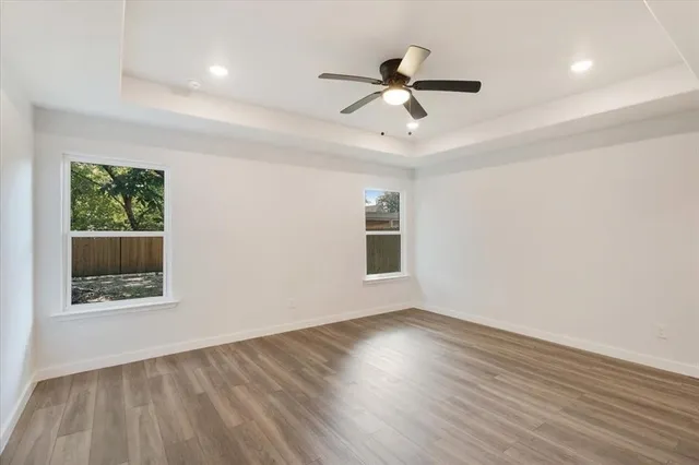 a view of empty room with wooden floor and fan