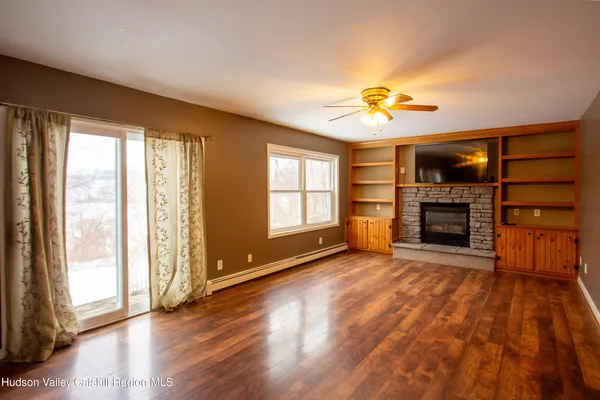 an empty room with windows fireplace and a ceiling fan