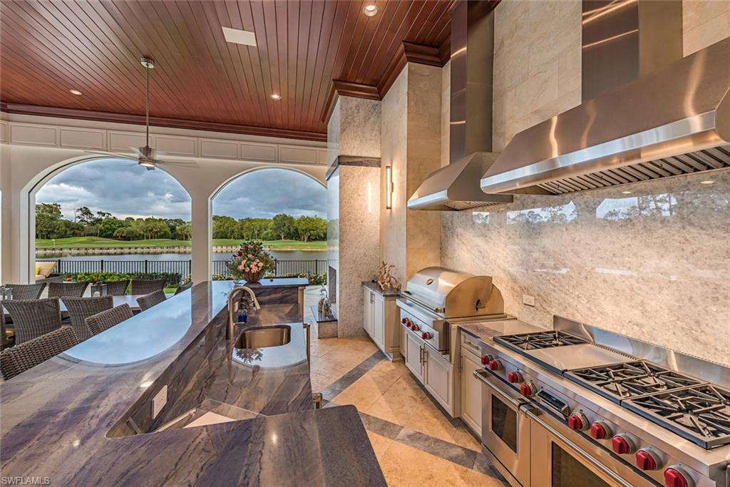 1420 Nighthawk Pointe Naples, FL 34105 - Photo 13 of 14 a kitchen with stainless steel appliances granite countertop a stove and a view of living room with furniture