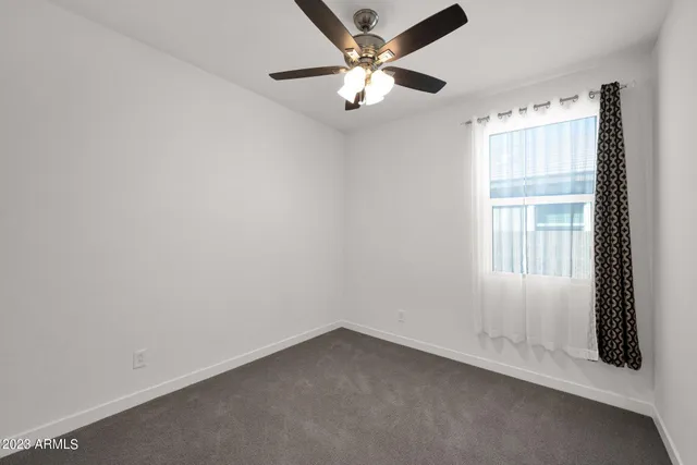 an empty room with a window and a fan