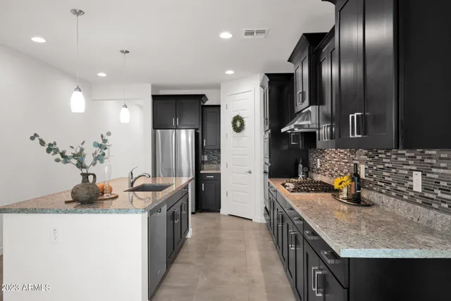 a kitchen with stainless steel appliances granite countertop a sink a stove and a refrigerator