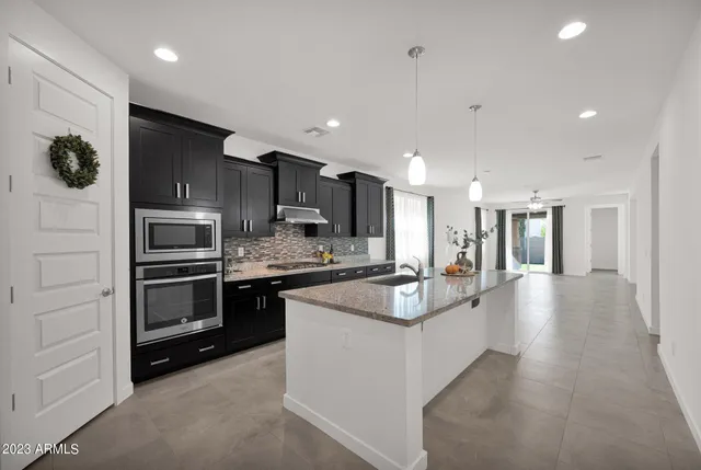 a large kitchen with kitchen island a large counter top stainless steel appliances and cabinets