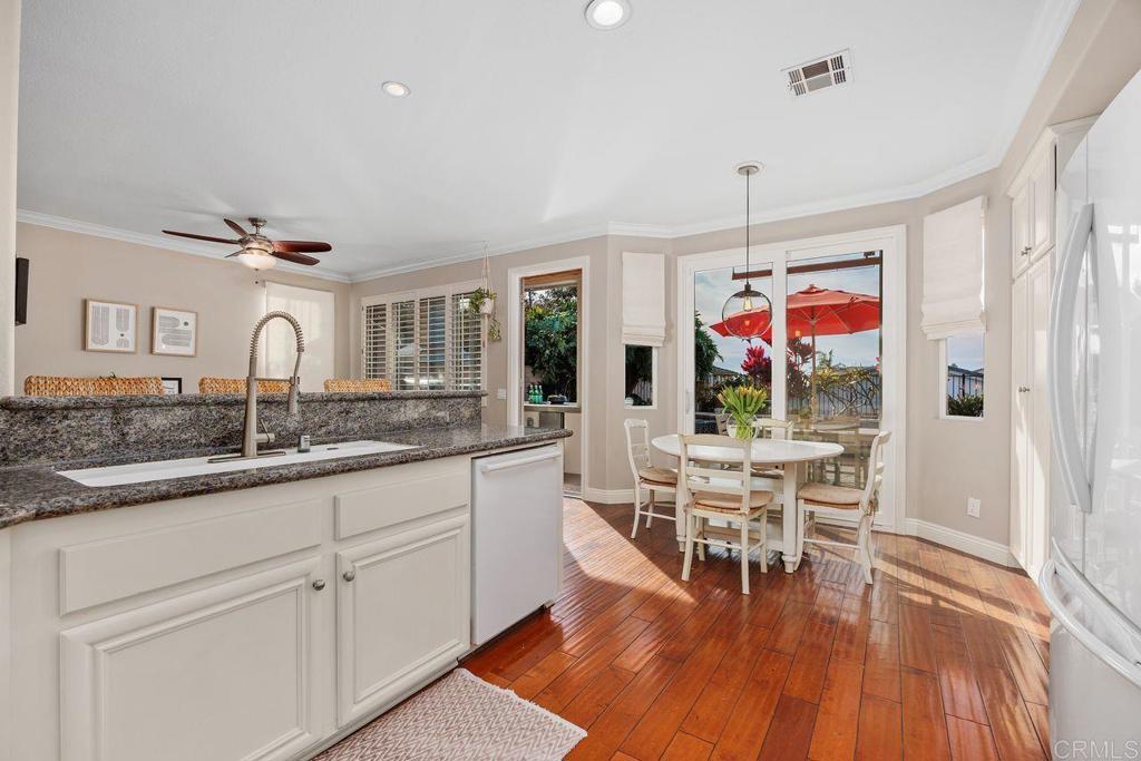 6707 Blue Point Drive Carlsbad, CA 92011 - Photo 19 of 43 a dining hall with stainless steel appliances granite countertop a stove and white cabinets with wooden floor