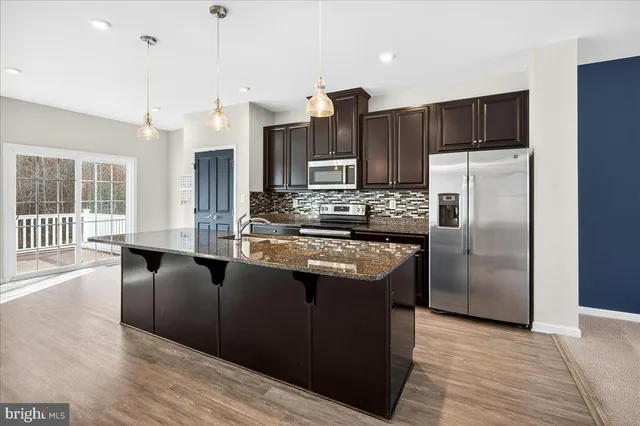 a kitchen with stainless steel appliances granite countertop a refrigerator a sink a stove and oven