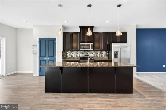 a kitchen with stainless steel appliances kitchen island granite countertop a refrigerator and a stove top oven