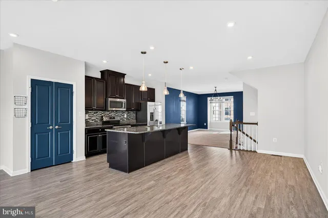 a kitchen with stainless steel appliances kitchen island granite countertop wooden floors and wooden cabinets