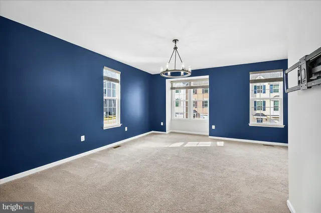 a view of empty room with windows and chandelier