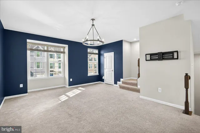 a view of a livingroom with a chandelier a ceiling fan and windows