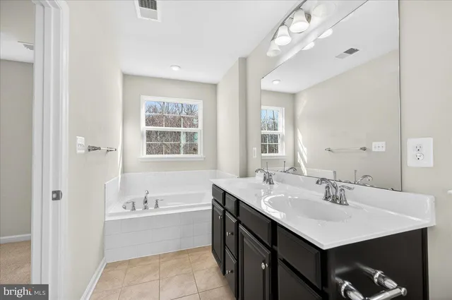 a bathroom with a sink double vanity granite tub shower and a mirror