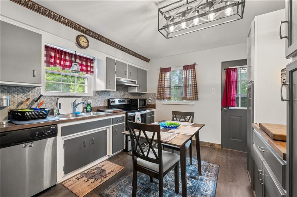 1241 Cochran Road Pittsburgh, PA 15243 - Photo 8 of 30 a kitchen with stainless steel appliances granite countertop a sink dishwasher a stove a refrigerator a microwave oven with a dining table and chairs with wooden floor