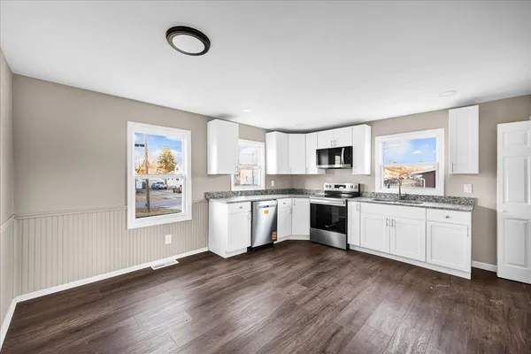 a large kitchen with cabinets wooden floor and stainless steel appliances