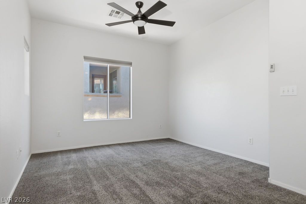 754 Solitude Point Avenue Henderson, NV 89012 - Photo 22 of 38 An airy bedroom with a ceiling fan above, complemented by soft carpet flooring.