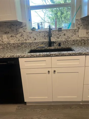 a view of kitchen with granite countertop white cabinets and a granite counter top