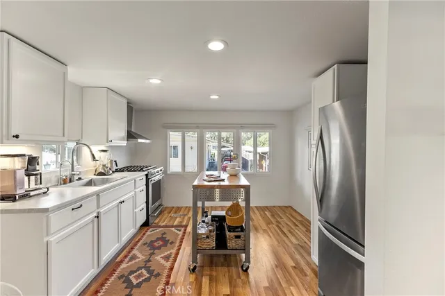 a kitchen with kitchen island a counter top space a sink stainless steel appliances and cabinets