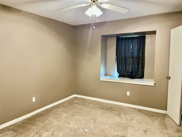 an empty room with a window and a ceiling fan