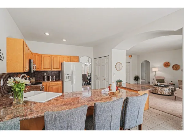 a dining hall with stainless steel appliances kitchen island granite countertop a table chairs and a view of living room