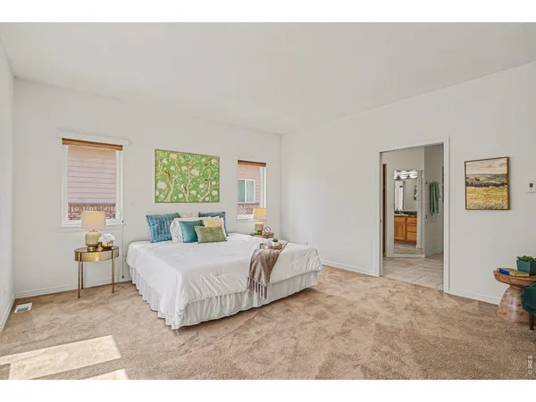 a bedroom with a bed painting on wall and two windows