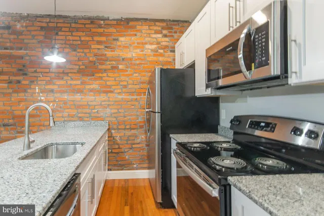 a kitchen with granite countertop cabinets stove top oven and sink