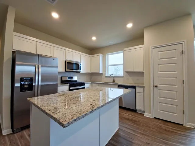 a kitchen with kitchen island granite countertop a stove and a refrigerator
