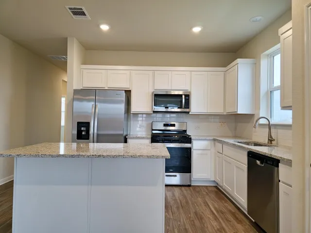 a kitchen with stainless steel appliances a sink a stove a microwave a sink a refrigerator and cabinets