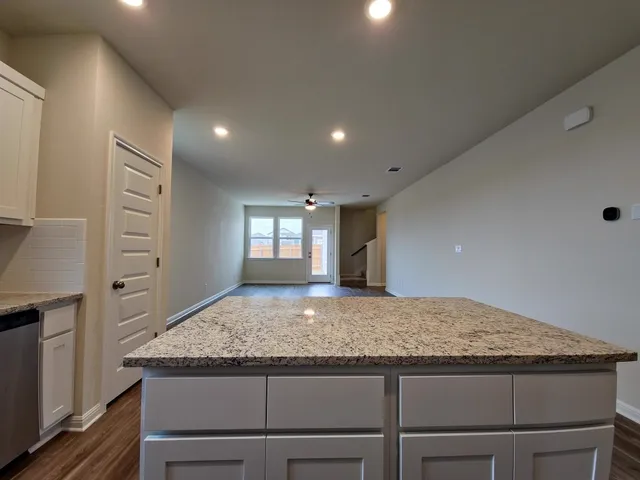 a kitchen with granite countertop kitchen island a sink stove and cabinets
