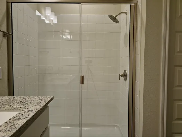 a bathroom with a granite countertop shower and a sink