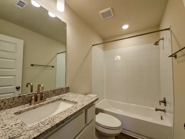 a bathroom with a granite countertop sink toilet and shower