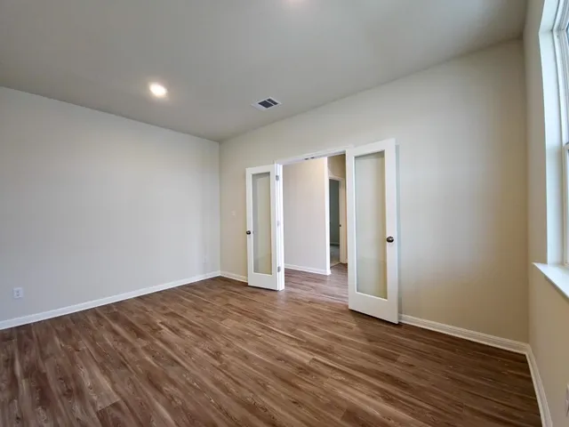a view of an empty room with wooden floor and closet