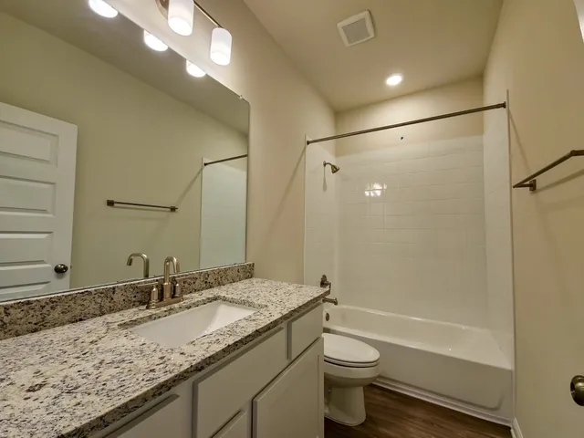 a bathroom with a granite countertop sink toilet and shower
