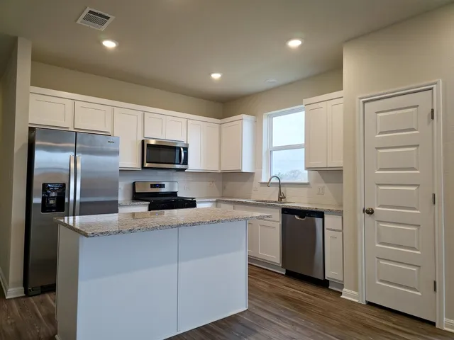 a kitchen with kitchen island granite countertop appliances cabinets and a sink