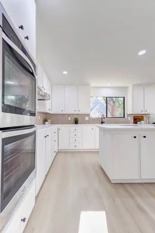 a kitchen with white cabinets and stainless steel appliances