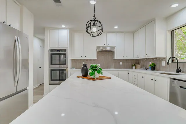 a kitchen with white cabinets and stainless steel appliances