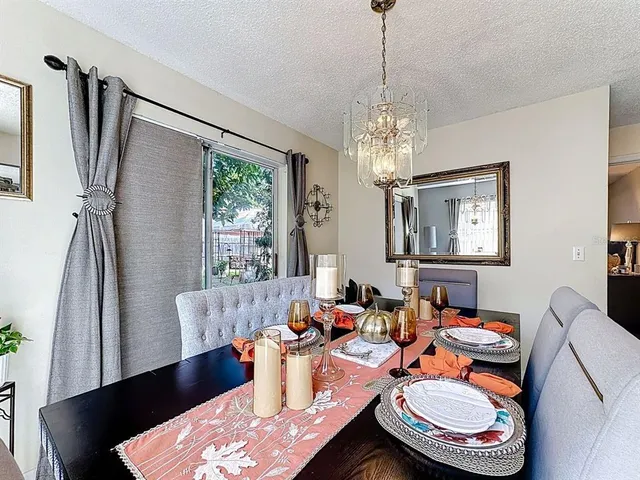 a dining room with wooden floor a chandelier a glass table and chairs
