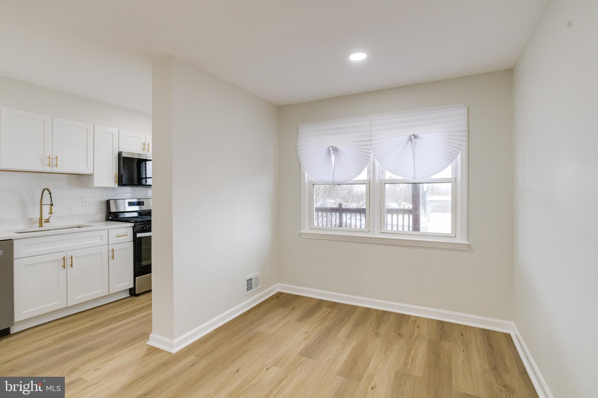 3916 2nd Street Baltimore, MD 21225 - Photo 4 of 20 a kitchen with granite countertop white cabinets a sink a window and stainless steel appliances